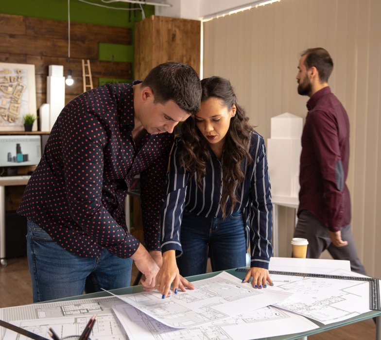 Two fellow architects standing at the table and discussing the project. Modern office